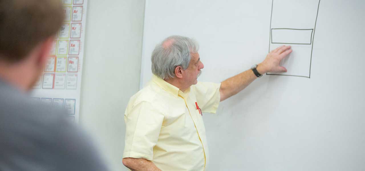 Physics professor explaining a concept using the white board